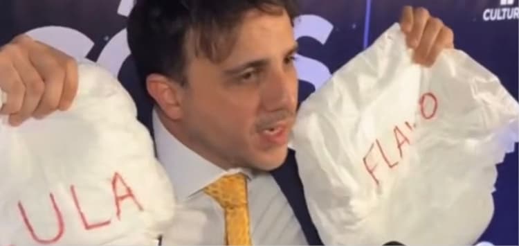 (Vídeo)Renan Santos chega ao debate da Band com duas fraldas destinadas a Lula e Flávio Bolsonaro e chama os dois de “cagões” pela ausência no debate